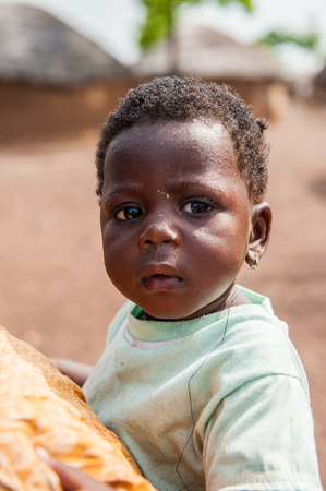 ACCRA, GHANA - MARCH 6, 2012: Unidentified Ghanaian boy on a back of his brother in the street in Ghana. Children of Ghana suffer of poverty due to the unstable economic situationのeditorial素材