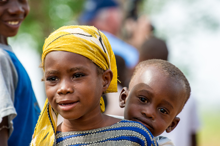 ACCRA, GHANA - MARCH 6, 2012: Unidentified Ghanaian beautiful girl carries her little brother on her back in the street in Ghana. Children of Ghana suffer of poverty due to the unstable economic situationのeditorial素材