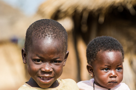 ACCRA, GHANA - MARCH 6, 2012: Unidentified Ghanaian boy holds his little brother on his hands in the street in Ghana. Children of Ghana suffer of poverty due to the unstable economic situationのeditorial素材