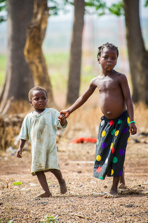 ACCRA, GHANA - MARCH 6, 2012: Unidentified Ghanaian girl walks with her little sister in the street in Ghana. Children of Ghana suffer of poverty due to the unstable economic situationのeditorial素材