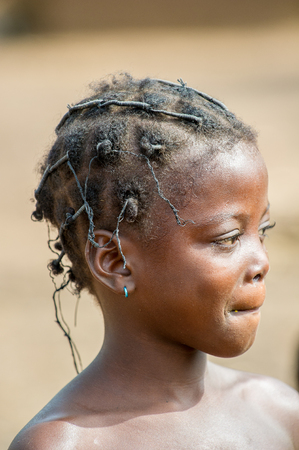 ACCRA, GHANA - MARCH 6, 2012: Unidentified Ghanaian beautiful girl with pigtails in the street in Ghana. Children of Ghana suffer of poverty due to the unstable economic situationのeditorial素材