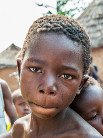 ACCRA, GHANA - MARCH 6, 2012: Unidentified Ghanaian girl carries her little brother on his back in the street in Ghana. Children of Ghana suffer of poverty due to the unstable economic situationのeditorial素材
