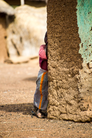 ACCRA, GHANA - MARCH 6, 2012: Unidentified Ghanaian girl stays near the house in the street in Ghana. Children of Ghana suffer of poverty due to the unstable economic situationのeditorial素材