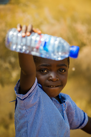 ACCRA, GHANA - MARCH 6, 2012: Unidentified Ghanaian boy with an empty bottle of water in the street in Ghana. Children of Ghana suffer of poverty due to the unstable economic situationのeditorial素材