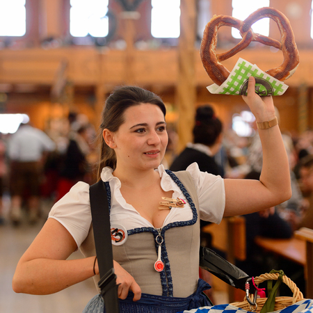 MUNICH, GERMANY - OCT 2, 2017: Unidentified girl in traditional Bavarian costume sells bread at the Octoberfest,  the world's largest festivalのeditorial素材