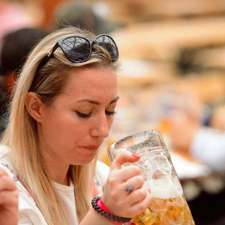 MUNICH, GERMANY - OCT 2, 2017: Unidentified girl drinks beer in traditional Bavarian costume at the Octoberfest,  the world's largest festivalのeditorial素材