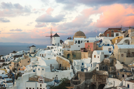 Image of white city on a slope of a hill at sunset and pink clouds, Oia, Santorini, Greeceの写真素材