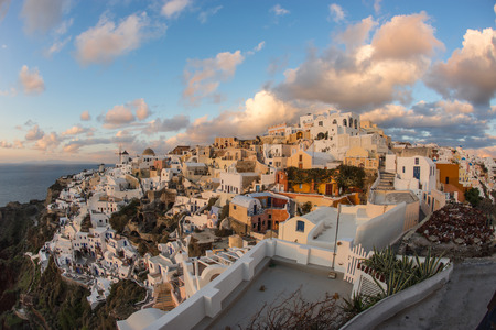 Image of white city on a slope of a hill at sunset and pink clouds, Oia, Santorini, Greeceの写真素材