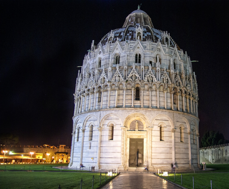 Baptistry of St John near the leaning tower of Pisa in Italy against a dark night skyの写真素材
