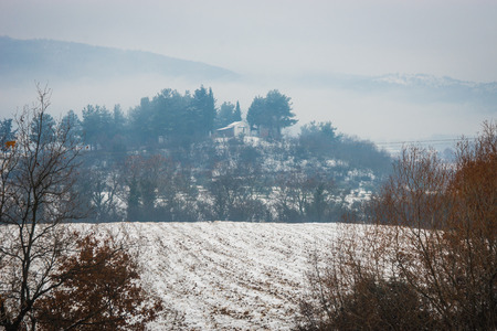 Beautiful landscape with small house on  hill, snow and fog near Edessa, Greeceの写真素材