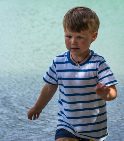 Image of a cute little boy playing on the shore of the lakeの写真素材