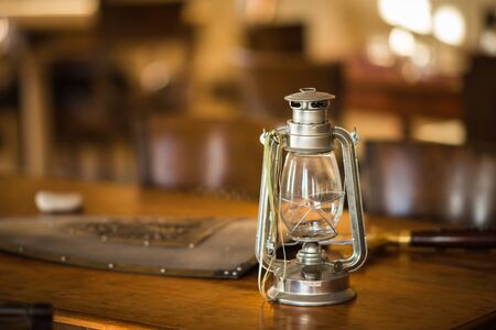 Image of kerosene lamp, shield and  sword on old wooden table