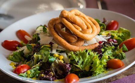 Image of salad of green leaves, cherry tomatoes and bread spiralsの写真素材