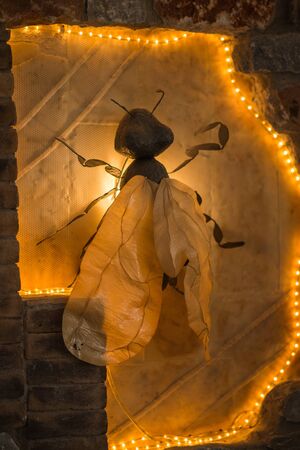 Image of huge decorative fly in  festively illuminated niche in wall