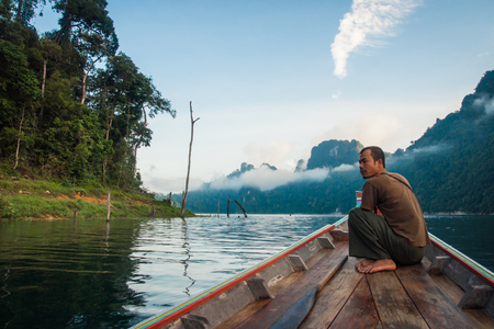 Chieou Laan lake, Thailand - January 12, 2011,  Guide on the lake in the boat at Chieou Laan lake, Thailandのeditorial素材