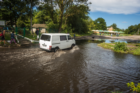 Baltiysk, Russia - August 22, 2017, Car moving deep in a puddle after a rain on Baltic spit, Russiaのeditorial素材