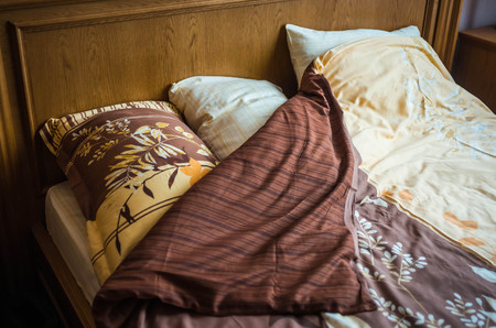 Image of beautifull linens, pillows and blankets on brown wooden bed