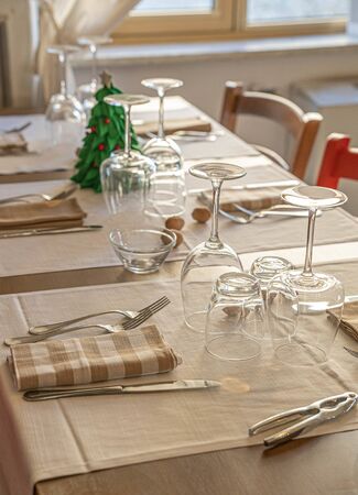 Image of dinner table with a small Christmas tree and sprinkled walnuts, selective focusの写真素材
