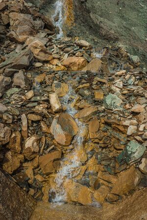 Image of small waterfall on  colored slope near  mountain road in Greece