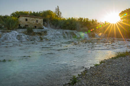 Rays of the rising sun over the thermal waters of the wild river in Saturnia in Tuscany in Italyの写真素材