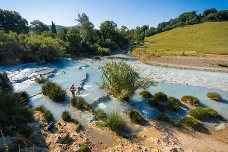 Saturnia, Italy - June 24, 2020, Two asian children taking bath in natural spa with waterfalls and hot springs at thermal baths in Saturnia, Tuscany in Italyのeditorial素材