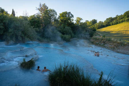 Saturnia, Italy - June 24, 2020, Two asian children taking bath in natural spa with waterfalls and hot springs at thermal baths in Saturnia, Tuscany in Italyのeditorial素材