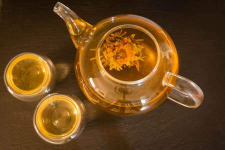 Image of white tea with flowers in a glass transparent teapot and small glass cupsの写真素材
