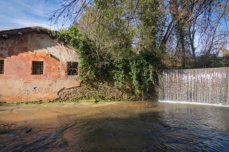 Image of waterfall and a pink picturesque wall of house near Isola Farnese, favorite walking place of Italiansの写真素材