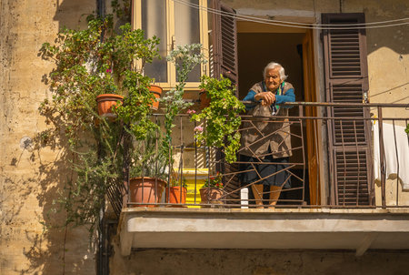 Orte, Italy - October 13, 2020, Old woman on balcony in medieval town of Orte in Italyのeditorial素材