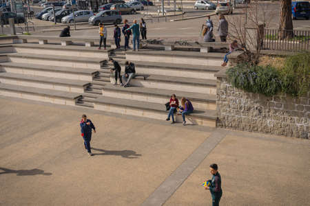 Viterbo, Italy - February 23, 2021, Young people in masks having a rest on the steps of the square...