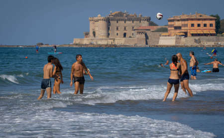 Marina di San Nikola, Italy - September 05, 2021, Family playing ball in waves on the beach against the background of the castle in Marina San Nicola in Italyのeditorial素材