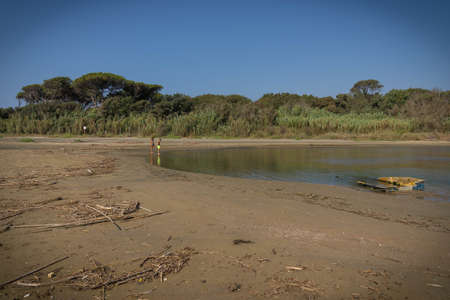 Torre Astura, Italy - September 12, 2021, Two persons and their reflection in the river flowing into the sea at Torre Astura in Italyのeditorial素材