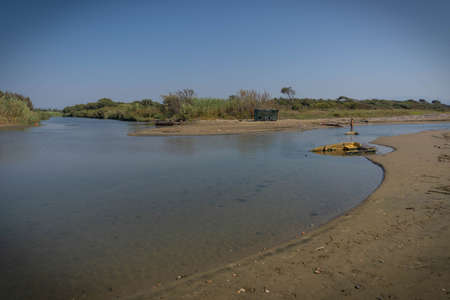 Torre Astura, Italy - September 12, 2021, Woman and her reflection in the river flowing into the sea at Torre Astura in Italyのeditorial素材