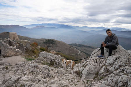 Rocca Calascio, Italy - October 30, 2021, Guy with dog in mountains of Rocca Calassio in Abruzzo, Italyのeditorial素材