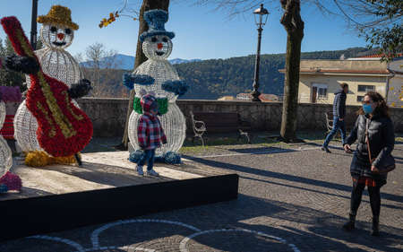 Alatri, Italy - December 12, 2021, Mother in medical mask walking with her daughter among New Year and Christmas decorations during pandemicof covid in Alatri, Italyのeditorial素材