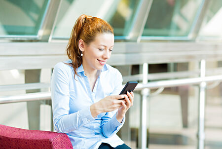 Closeup portrait, happy, cheerful, girl, excited by what she sees on cell phoneの写真素材