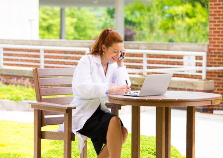 Closeup portrait, young smiling confident female doctor, healthcare professional talking on phone, giving consultation isolated background hospital park  Patient visit health care  Positive emotionsの写真素材