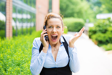Closeup portrait happy young beautiful woman looking excited, surprised in disbelief, receiving good news on phone itの写真素材