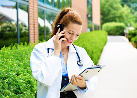 Closeup portrait, young smiling confident female doctor, healthcare professional talking on phone, giving consultation isolatedの写真素材