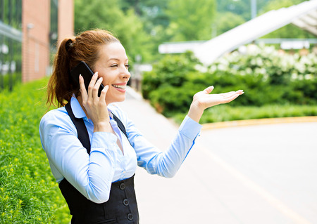 Closeup portrait smiling happy businesswoman talking on mobile phone. Business woman having conversation on cellphone standing outdoors.の写真素材