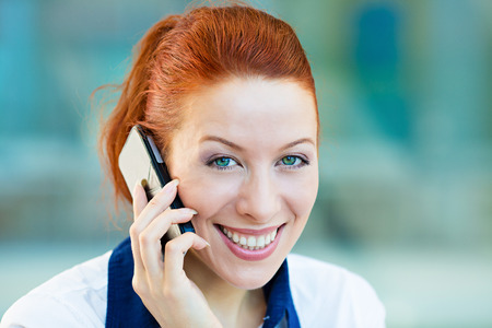 Closeup portrait, headshot happy, smiling businesswoman talking on mobile phone. Business woman having conversation on cellphone isolated corporate office windows background. Communication conceptの写真素材