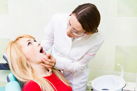 Closeup portrait young female dentist and patient seating in chairの写真素材