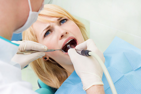 Closeup portrait young female, woman, patient sitting in dentist chairの写真素材