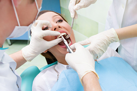Closeup portrait dentist, his assistant carrying out thorough examination dental procedureの写真素材