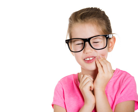 Closeup portrait young little girl with sensitive tooth ache, crown problem, touching outside mouth with hand, isolated white background. Negative human emotion, facial expression, feelings, reactionの写真素材