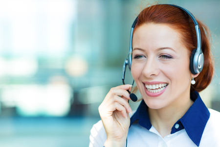 Closeup portrait young happy successful business woman, customer service representative, call centre worker, operator, support staff speaking with head set isolated background corporate office windowsの写真素材