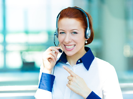 Closeup portrait young happy successful business woman, customer service representative, call centre worker, operator, support staff speaking with head set isolated background corporate office windowsの写真素材