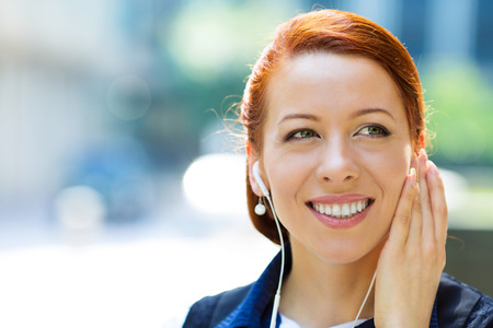 Closeup portrait attractive happy, smiling business woman walking on street listening to music outdoorsの写真素材