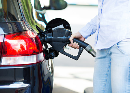 woman filling compact car tank with petrol at gas station