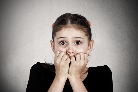 Closeup portrait young little girl biting her finger nailsの写真素材